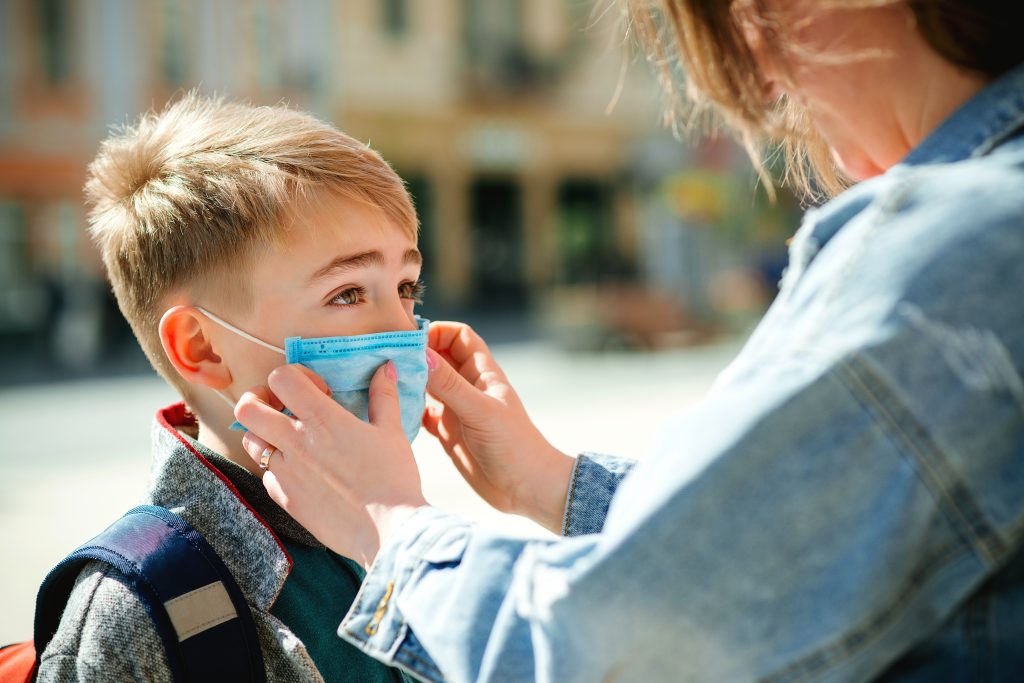 Mother putting face mask on her son