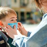 Mother putting face mask on her son
